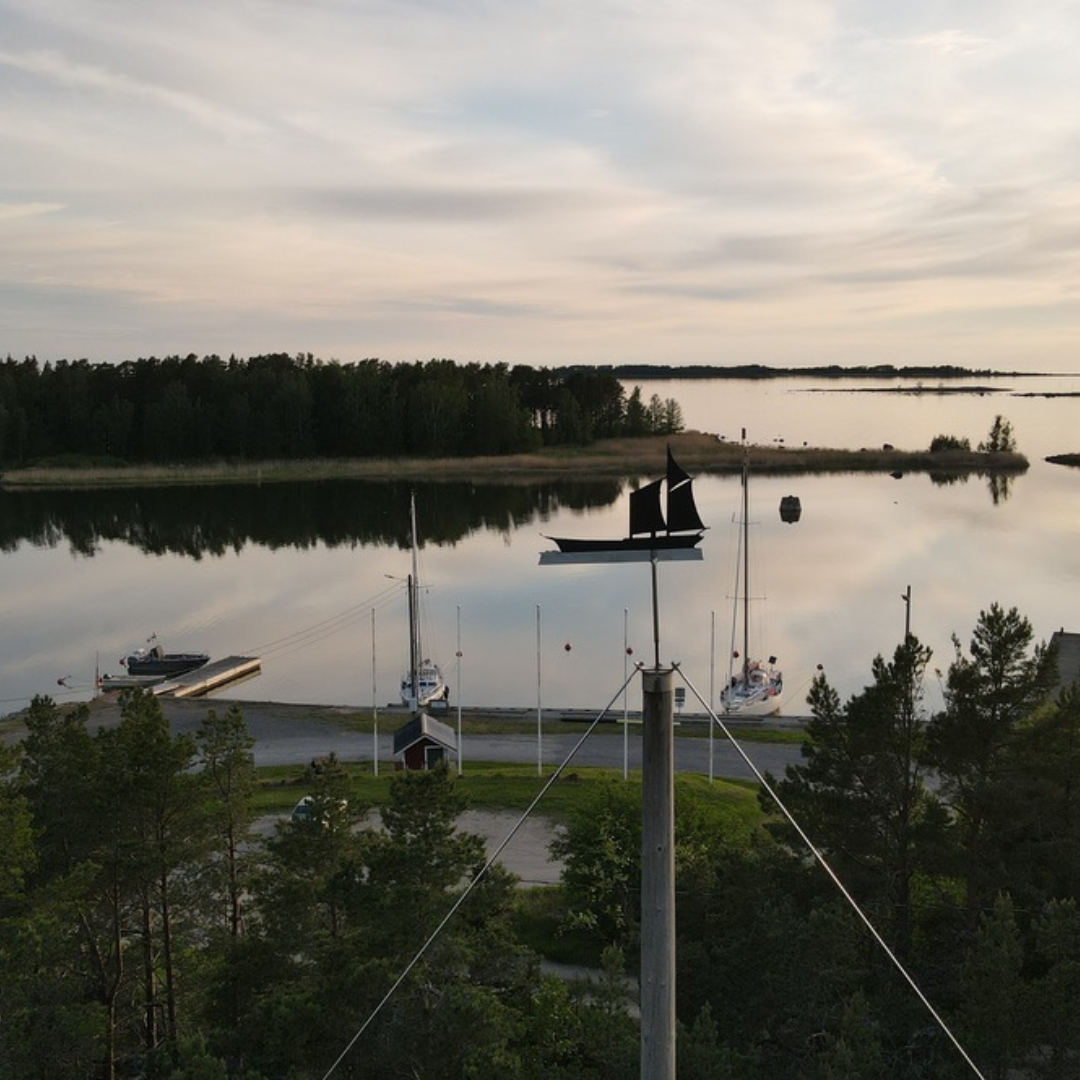 Utsikt över Kilens gästhamn med segelbåtar och svart väderflöjel i form av en skuta