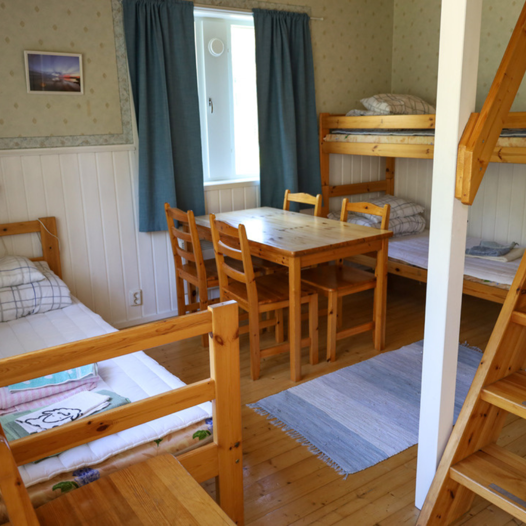 Majoitusrakennus Kiilin alueella – punainen hirsitalo metsän ja kulttuurimaiseman keskellä.