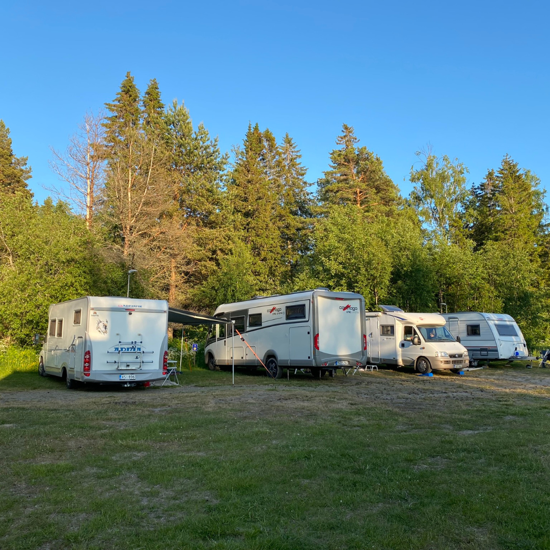 Husbilar uppställda på campingområdet vid Kilen, omgiven av sommargrön skog