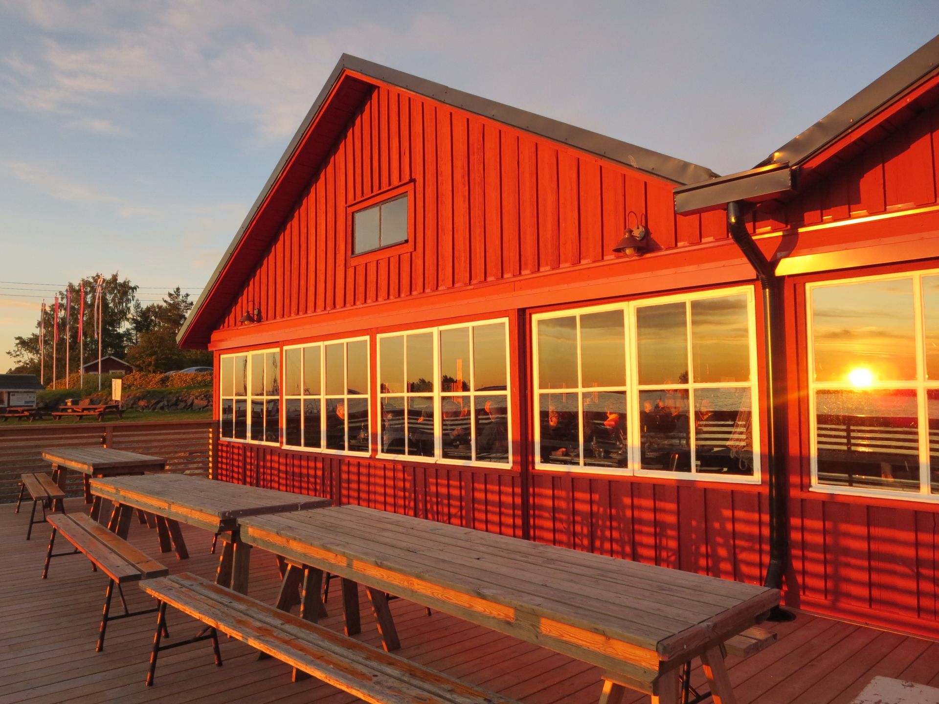 Salteriet vid solnedgång, speglingar i fönstren och bänkar på terrassen.