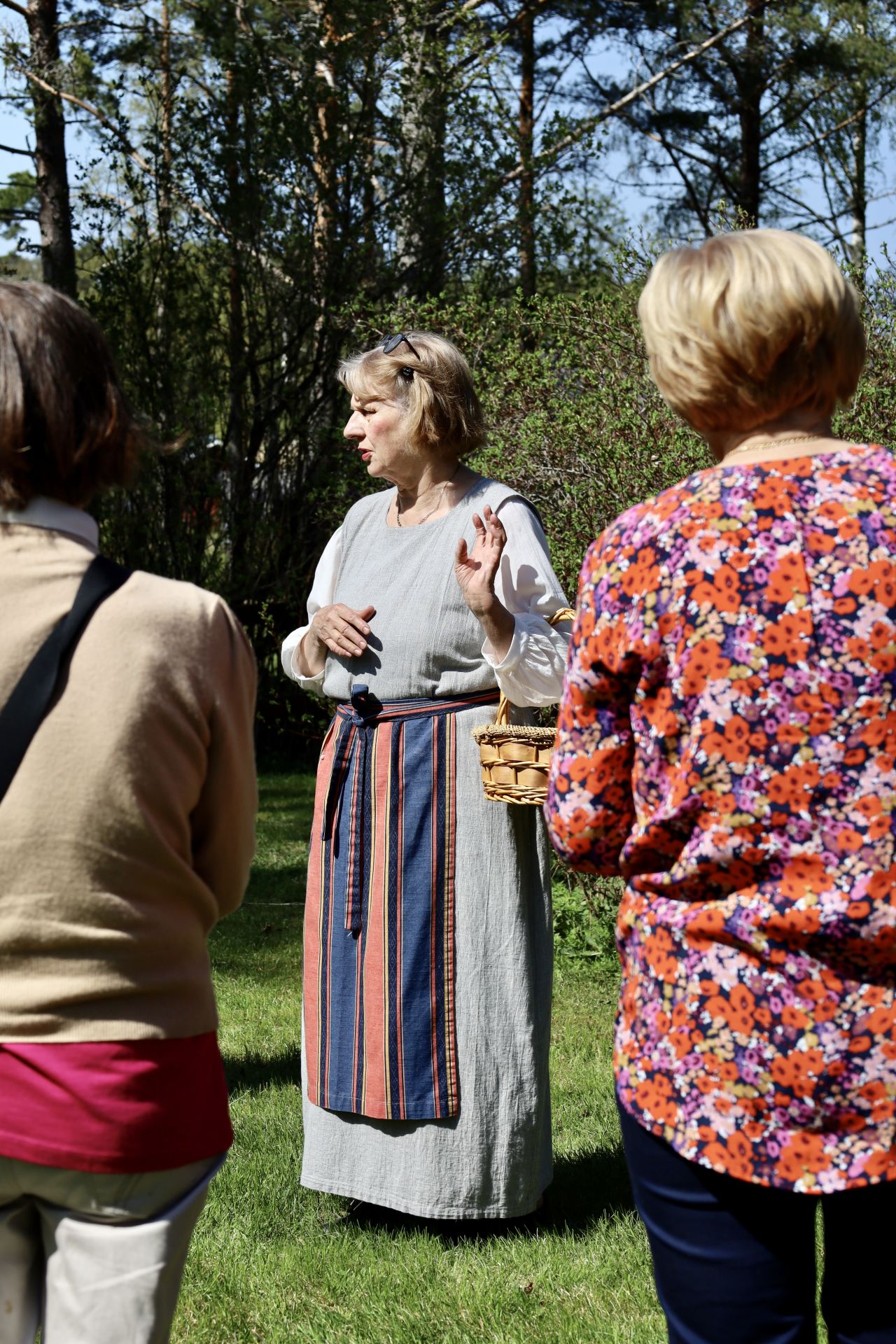 Guide i traditionell dräkt berättar för besökare under en guidad tur på Kilens hembygdsgård.