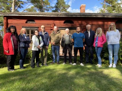 Kilenin kotiseutumuseon hallitus ryhmäkuvassa punaisen hirsirakennuksen edessä.
